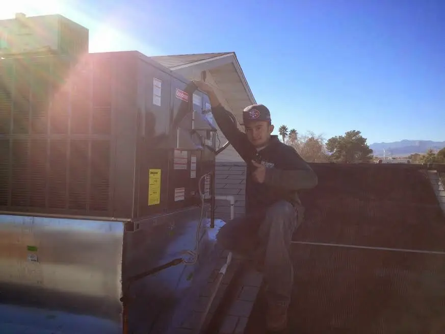 HVAC technician performing AC Tune-Up on a rooftop unit in Williston
