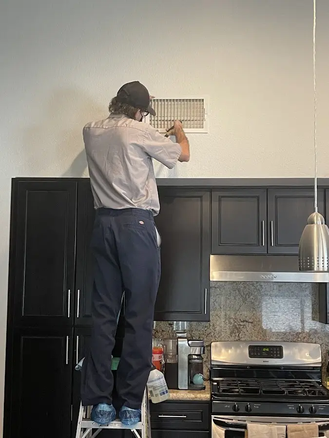 Technician inspecting an air vent during HVAC service in Williston